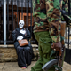 An armed police officer walks past an environmental protester wearing a skeleton costume as she demonstrates outside parliament against recent government plans to mine coal and open a coal-fired power plant, in downtown Nairobi, Kenya Tuesday, June 5, 2018. Kenyan activists protested plans for the joint venture between the Kenyan and Chinese governments in Lamu County, saying it will have devastating effect on the environment and health of local populations.